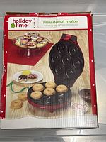 Box packaging front showing Holiday Time mini donut maker with six mini donuts on baking plate.