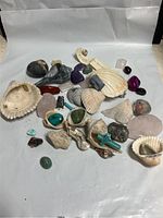 Collection of stones, shells, and pendants on white background showing overall lot contents.