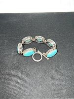 Bracelet laid flat showing full length, turquoise stones, filigree sterling silver, and toggle clasp.
