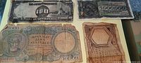 Photo showing five antique paper banknotes, including 100 Pesos and 5,000,000 units notes, all showing signs of heavy use and wear.