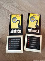 Front view of two unopened 1991 Mirrycle mountain bike mirrors in original packaging, showing yellow branding and product name.