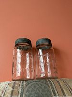Front view of two glass jars labeled Crown and Corona showing embossed glass and metal lids.