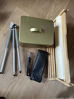 Full lot overview with art paper dispenser, metal box, and three tripods including one in pouch.