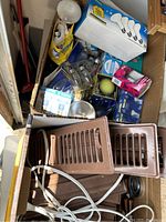 Box with assorted light bulbs including boxed and loose bulbs plus brown plastic vent covers and white cord