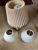 Overall view of the vintage lamp with large beige pleated shade and two smaller off-white shades on floor.