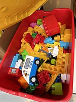 Photo showing red bin filled with assorted multicolored Mega Bloks pieces and police vehicle toy