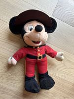 Full body image of the vintage Mickey Mouse plush dressed in a mounted police red uniform and brown hat, showing overall condition and details.