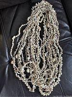 Full view of multiple natural shell strand necklaces laid out showing intertwined strands and variety of shell shapes and sizes.