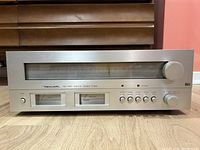 Front view of Realistic TM-1001 AM/FM stereo tuner showing silver faceplate with dual analog meters and control knobs.