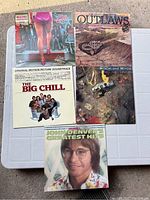 Five vintage vinyl records with covers showing various artists and titles including The Big Chill soundtrack and John Denver's Greatest Hits Volume 3