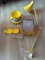 Photo of yellow vintage lot with Luxo lamp, mechanical scale, file holder case, and wall hooks on wooden floor