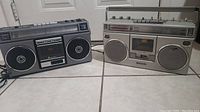 Two vintage boomboxes side by side, the Quasar on the left and Panasonic on the right