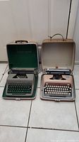 Two vintage Royal typewriters in their hard cases, Open cases showing typewriters and some wear. Left typewriter green, right beige.