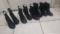 Four pairs of black Forever 21 peep toe knit booties displayed in a row against a tiled floor, showcasing the full height and shape of each bootie.