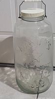 Side view showing the large glass mason jar with metal handle and white lid.