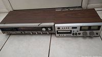 Two vintage 8-track players side by side showing front and top woodgrain cabinets.