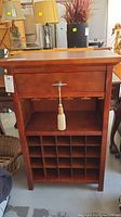 Front view of the wooden cabinet showing drawer, glass holders, and wine bottle compartments.