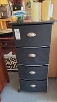 Front view of black cloth drawer unit showing four drawers with silver handles, labeled lot 21.