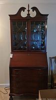 Full frontal view of the secretarial cabinet showing upper glass door section and lower drawers with slant front desk.