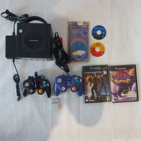 Full lot showing Nintendo GameCube console, controllers, memory card, power cord, AV cable, four game discs and cases, and replacement game cases.