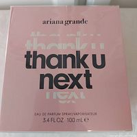 Front view of the pink Ariana Grande Thank U Next EDP box, showing brand name, product name, and size (100 ml).