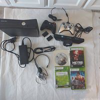 Complete Xbox 360S lot showing console, two controllers, rechargeable battery packs, charging cord, power supply, HDMI cord, Kinect motion sensor, headset, and four game cases plus one loose game disc.