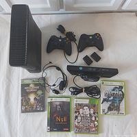 Full overview photo showing Xbox 360S console, two controllers (wired and wireless), two AA battery pack holders, Kinect motion sensor, wired headset, and four Xbox 360 game cases.