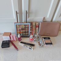 Photo of full lot with Kendall and Kylie Jenner pouch, eyeshadow palette, face creams, primers, lip gloss, nail polish, mascaras, and eyeliners arranged on a surface.