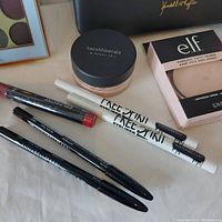 Photo showing assorted makeup items including eyeliners, lip crayons, face powder, primer and Kendall and Kylie pouch visible in background