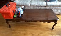 Rectangular wood coffee table with one drawer and carved cabriole legs showing surface marks, chips, and scratches