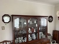 Photo showing two framed plates and a wooden block clock displayed on a wall.