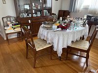 Six wood frame dining chairs around a dining table with various items on it, showing the overall style and condition.
