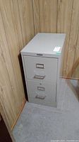 Front view of the gray metal filing cabinet showing the two drawers and label holders.