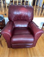 Front view of red leather recliner chair showing padded seat, back, and arms with creased leather.