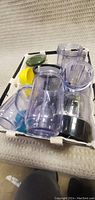 Contents of the lot including multiple clear plastic blender cups with some screw-on lids, a blade assembly, and the main blender base.