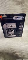 Box of DeLonghi cappuccino maker with product photo and branding on front.