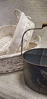 Photo showing metal drink caddy with bee design and two white wicker baskets with cloth liners.