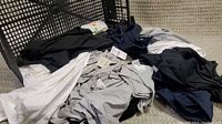 Pile of various women's tops in black, white, gray, and navy colors shown.