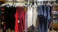 Full view of the rack holding various new women's tops and dresses in different colors including black, red, pink, white, blue stripes, and purple.