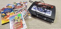 Photo of PlayStation 3 console, game cases including Shrek Fairy Tale and The Secret Nine DVDs, wires, and Pegaso DVD player unit