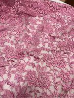 Close-up view of floral pink stretchy lace showing texture and details of embroidery on sheer fabric.