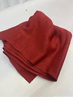 Folded piece of red damask fabric showing the color and woven pattern details.