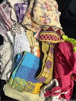 Overview photo showing assorted estate linens including placemats, floral tablecloths, napkins, and curtains in various colors and patterns.