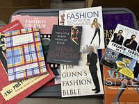 Top view of fashion and design books arranged on a gray surface, showing various titles on style, fashion illustration, and vintage guides.