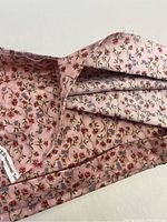 Close-up of the pink floral patterned cotton fabric showing the detailed floral print with small flowers in red, blue, and green on a pink background.