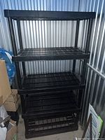 Full front view of the black storage rack showing all five shelves assembled vertically in a storage unit.