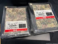 Photo showing six black tapestry-style photo albums stacked and sealed in plastic, with labels indicating capacity for 304 4x6 photos.