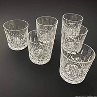 Six glasses arranged on black background, angled front view shows cut pattern