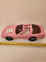 Side view of pink Barbie Corvette toy car measuring approximately 17 inches in length, showing white interior seating and black wheels.