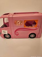 Side view of pink Barbie Winnebago RV camper showing floral decorations and window with orange frame.